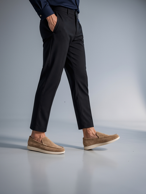 Person wearing black pants and brown shoes on a gray background