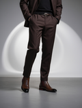 Person wearing a brown suit with a belt and shoes on a gray background